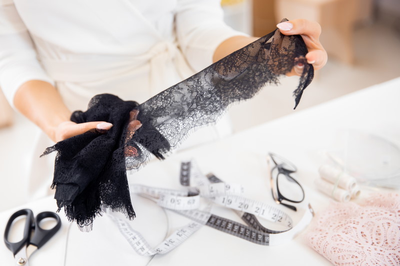Black lace in female hands, lingerie designer clothes in workplace.